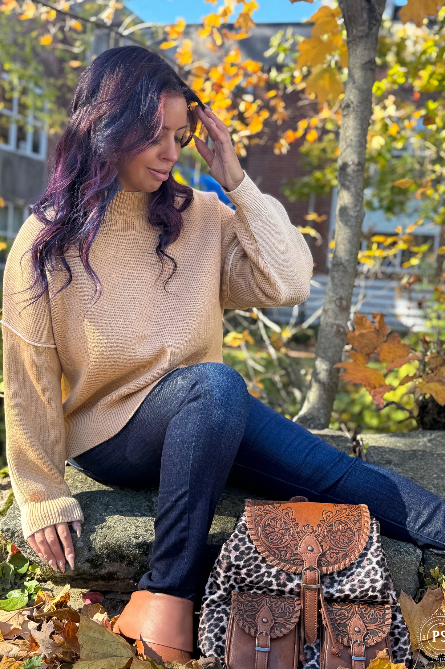 Woman sitting on a rock with a patterned bag in an autumn setting